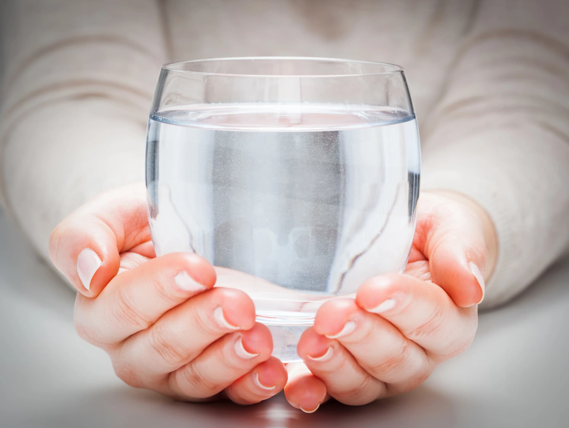 Verre d'eau rempli au robinet dans une cuisine lumineuse