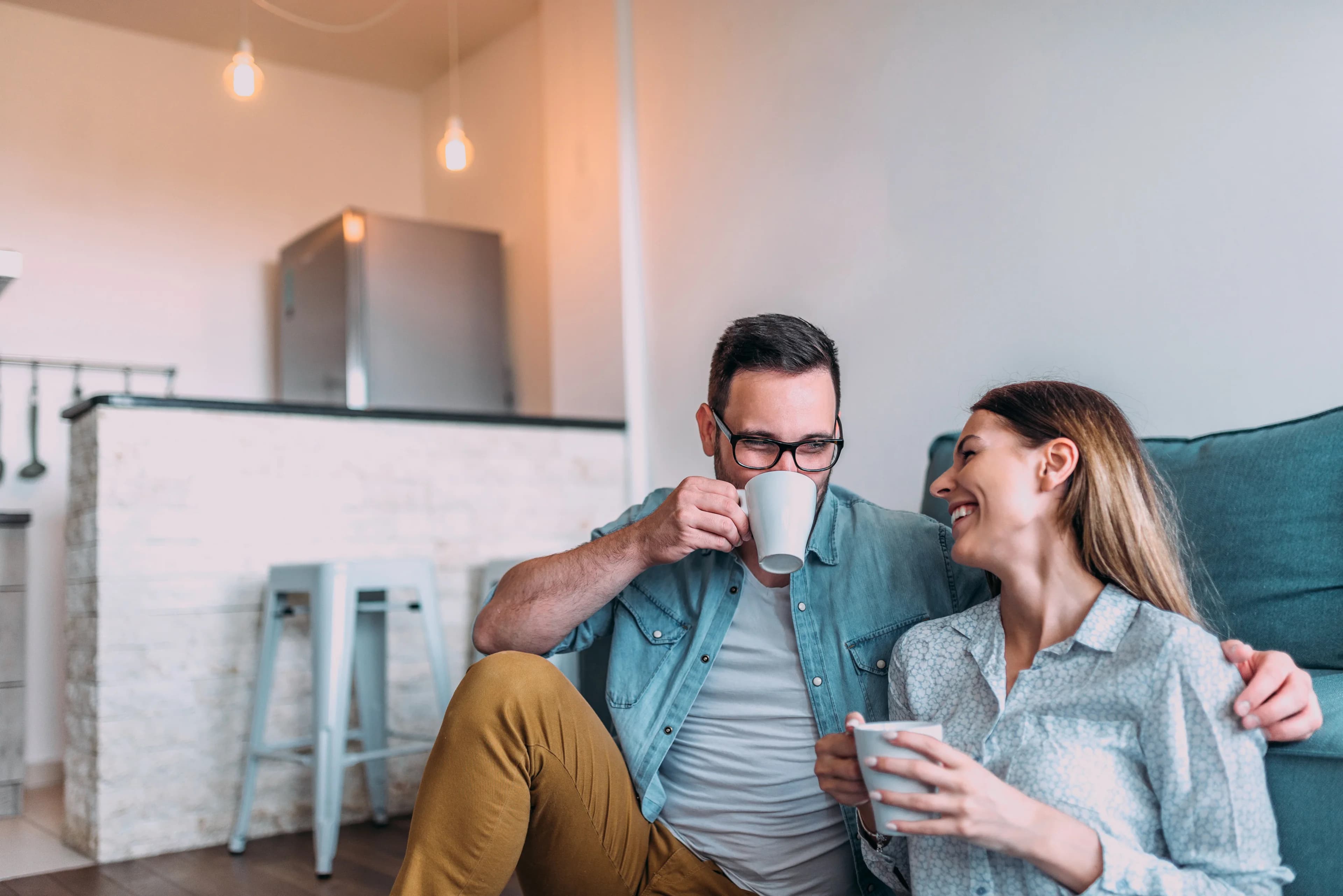 Un couple partage un café sur le canapé de son salon