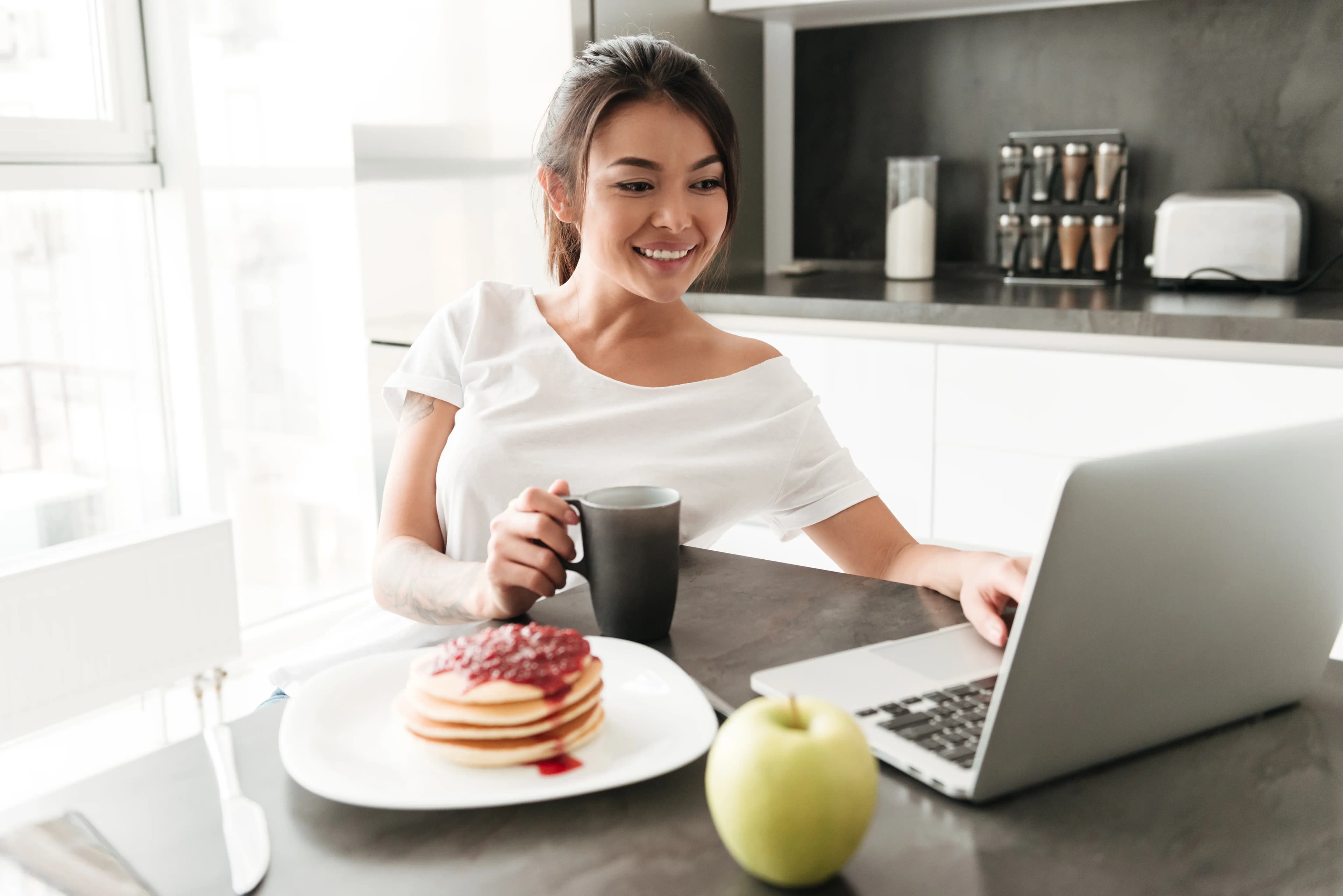 Une cliente consulte son devis Technodouce sur son ordinateur au petit-déjeuner