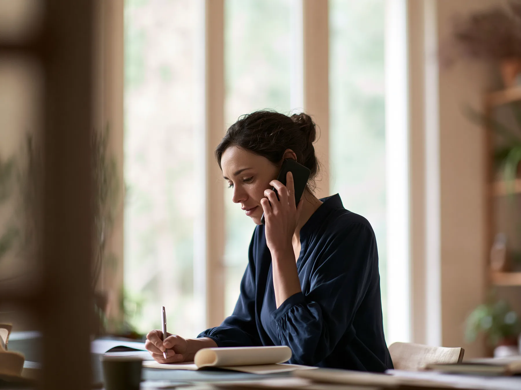 Une cliente au téléphone avec son interlocuteur Technodouce, prenant des notes à son bureau
