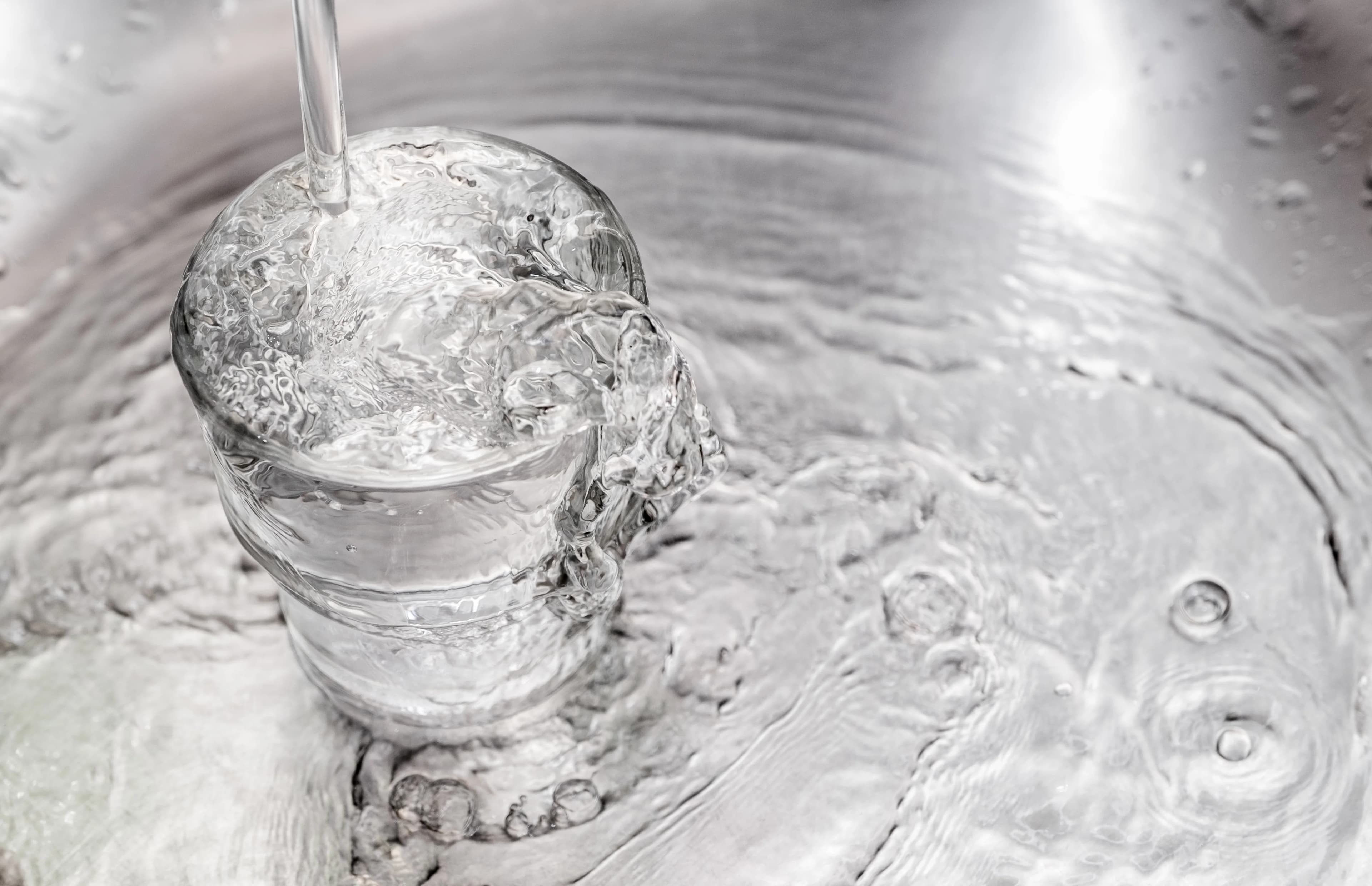Verre d'eau servi au robinet dans une cuisine d'appartement